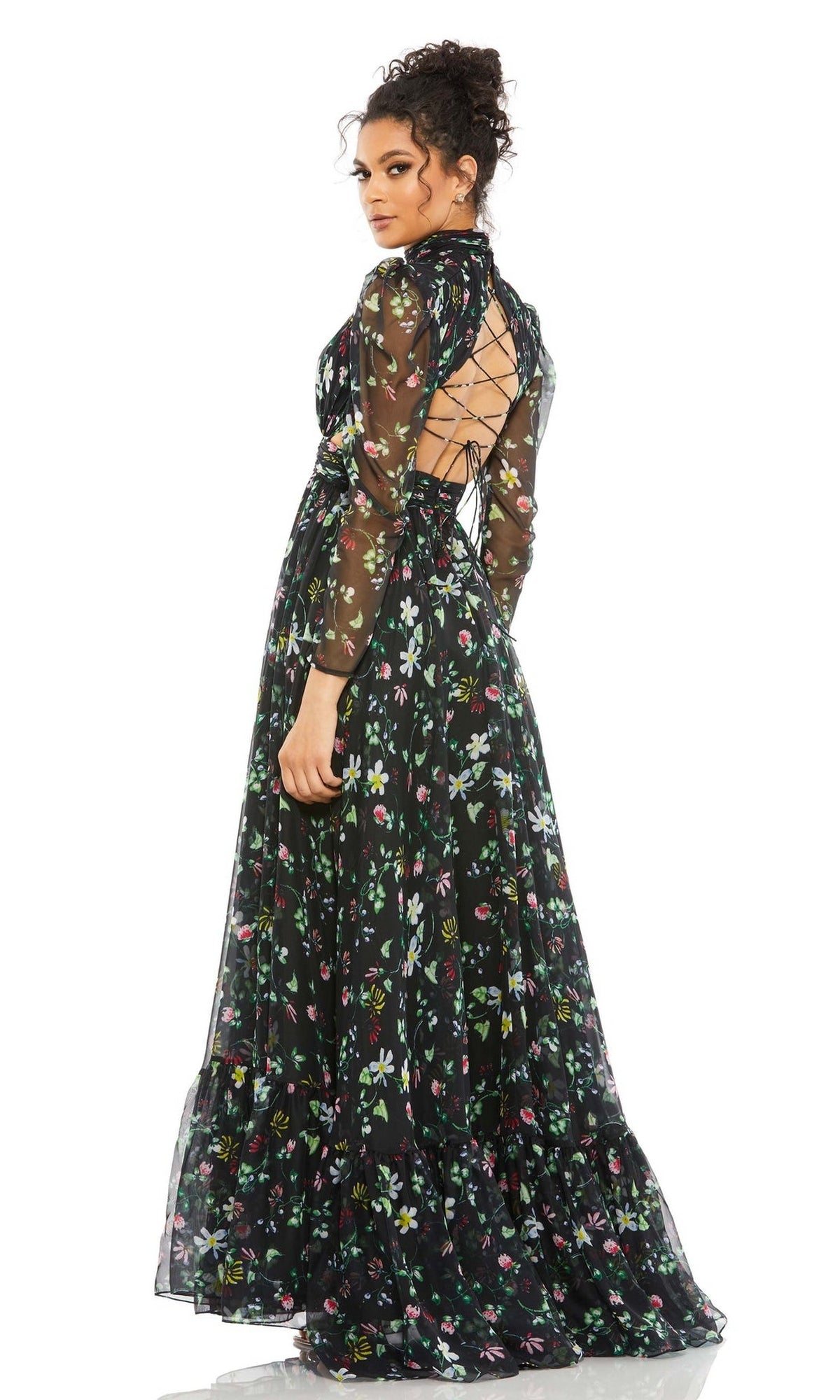 Woman in the Mac Duggal 67942 long black print formal dress with sheer long sleeves and lace-up open back, standing and looking over her shoulder.